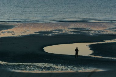 Opal Coast, Wissant, Fransa sahilinde su yüzeyinin önünde duran yetişkin bir adamın silueti.