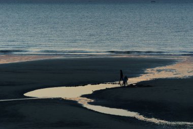 Kuzey Denizi 'nin önünde Opal Coast, Wissant, Fransa sahillerinde duran insanların silueti.