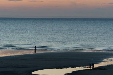 Kuzey Denizi 'nin önünde Opal Coast, Wissant, Fransa sahillerinde duran insanların silueti.