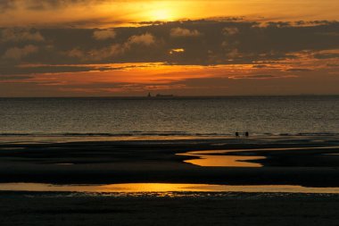 Renkli günbatımında kuzey denizinde, Opal Coast, Wissant, Fransa sahillerinde oturan iki kişinin silueti.