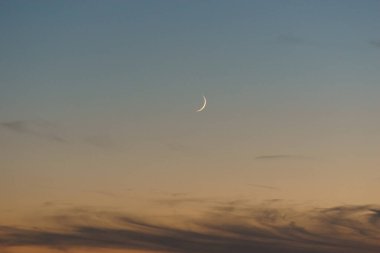 Akşamları alacakaranlıktaki hilal gökyüzünde gün batımından sonra renkli güneş ışığıyla
