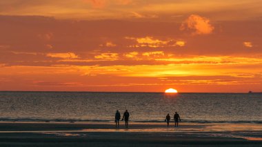 Gün batımında, Opal Coast, Wissant, Fransa sahillerinde kuzey denizinin önünde yürüyen bir grup insanın silueti.