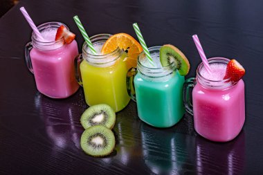 Siyah arka planda çeşitli meyvelerle hazırlanmış meyve suları