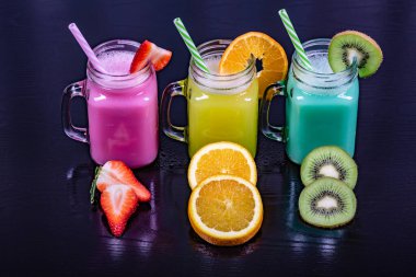 Siyah arka planda çeşitli meyvelerle hazırlanmış meyve suları