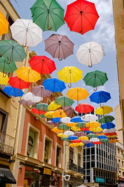 Sokak renkli şemsiyelerle kaplı.