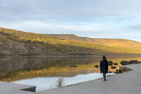 Gölün kenarındaki kadın dağları yansıtıyor. Sanabria Gölü, İspanya.