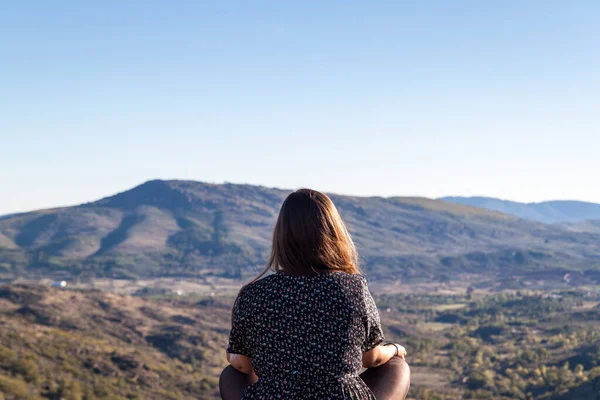 Arkadaki kadın dağ manzaralı meditasyon pozisyonunda oturuyor. Yüksek kalite fotoğraf