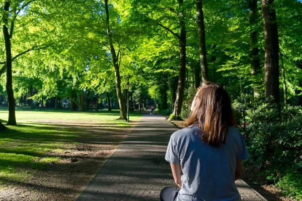 Young woman riding a bicycle on a walk in the middle of a park. 