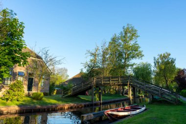 Kanalın yanındaki Hollanda mimari evinde kırmızı bir tekne ve ahşap bir köprü var. Yüksek kalite fotoğraf