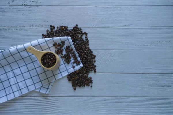 Coffee scoop and Coffee beans with tablecloth beside top view isolated on white wooden background