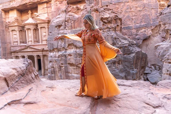 背景の岩の上に残る伝統的な服やスカーフを着た女性はペトラ宮殿です — ストック写真