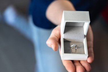 Evlilik teklifi yüzüğü bir kutunun içinde dizlerinin üstünde duruyor.