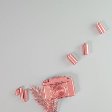 Altın Gül Retro fotoğraf makinesi. İçinde film kasetleri ve palmiye yapraklı pastel renkli arka planda piller var. 70 'lerin hafif ve metalik kompozisyonu.