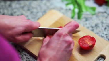 Person cutting tomatoes on a wooden board