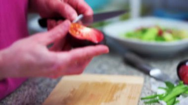 Person cutting tomatoes in the kitchen