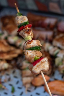 Tavuk göğsü ve domuz eti taze renkli ve lezzetli sebzelerle ahşap şişte çekiliyor.