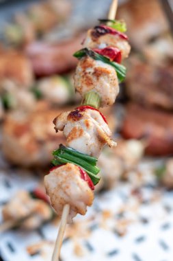 Tavuk göğsü ve domuz eti taze renkli ve lezzetli sebzelerle ahşap şişte çekiliyor.