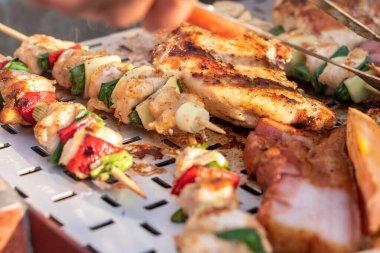 Tavuk göğsü ve domuz eti taze renkli ve lezzetli sebzelerle ahşap şişte çekiliyor.