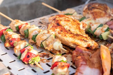 Tavuk göğsü ve domuz eti taze renkli ve lezzetli sebzelerle ahşap şişte çekiliyor.