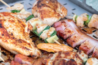 Tavuk göğsü ve domuz eti taze renkli ve lezzetli sebzelerle ahşap şişte çekiliyor.