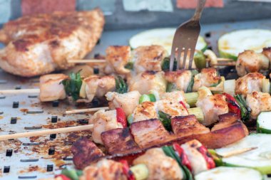 Tavuk göğsü ve domuz eti taze renkli ve lezzetli sebzelerle ahşap şişte çekiliyor.