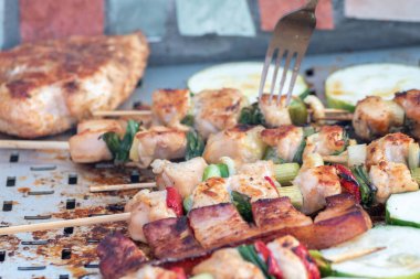 Tavuk göğsü ve domuz eti taze renkli ve lezzetli sebzelerle ahşap şişte çekiliyor.