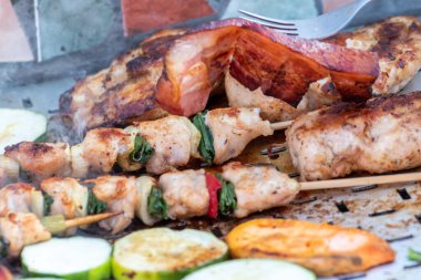 Tavuk göğsü ve domuz eti taze renkli ve lezzetli sebzelerle ahşap şişte çekiliyor.
