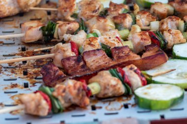 Tavuk göğsü ve domuz eti taze renkli ve lezzetli sebzelerle ahşap şişte çekiliyor.