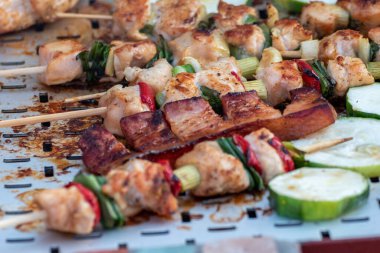 Tavuk göğsü ve domuz eti taze renkli ve lezzetli sebzelerle ahşap şişte çekiliyor.