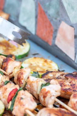 Tavuk göğsü ve domuz eti taze renkli ve lezzetli sebzelerle ahşap şişte çekiliyor.