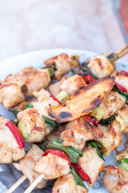 Tavuk göğsü ve domuz eti taze renkli ve lezzetli sebzelerle ahşap şişte çekiliyor.