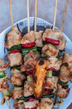 Tavuk göğsü ve domuz eti taze renkli ve lezzetli sebzelerle ahşap şişte çekiliyor.