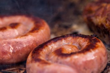 Close up shot of rolled up sausages on skewer placed over barbeque