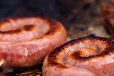 Close up shot of rolled up sausages on skewer placed over barbeque