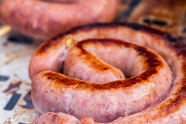 Close up shot of rolled up sausages on skewer placed over barbeque