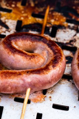 Close up shot of rolled up sausages on skewer placed over barbeque