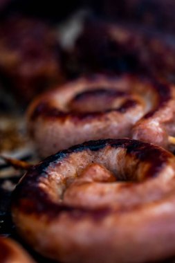 Close up shot of rolled up sausages on skewer placed over barbeque
