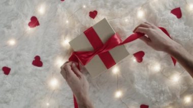 close up of hands preparing red bow for gift box