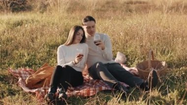 Kırmızı şarapla mutlu çift gün batımında bir tarlada 