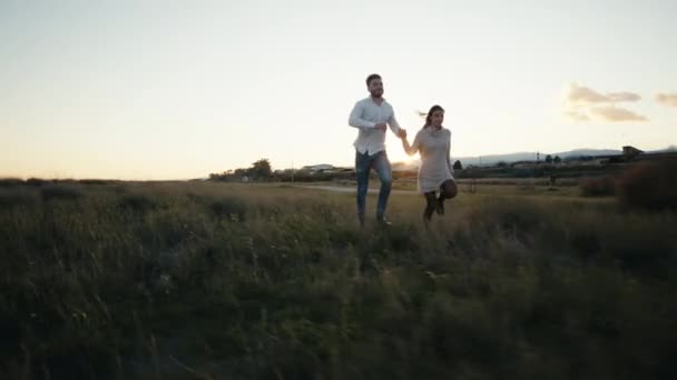 Couple Runs in a field at Sunset light — Αρχείο Βίντεο