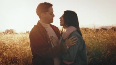 Çiftler gün batımında birbirlerine sarılırlar.