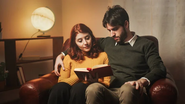 Paar liest gemeinsam ein Buch auf dem Sofa — Stockfoto