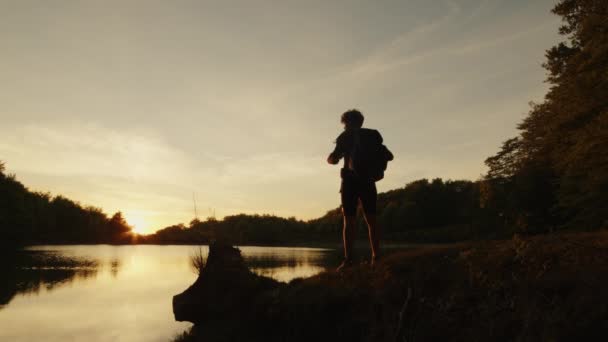 Αγόρι με σακίδιο περπατά κοντά στη λίμνη στα βουνά — Αρχείο Βίντεο