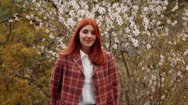 Szczęśliwa rudowłosa dziewczyna pod drzewem wiosennych kwiatów. nastrój wiosenny. — Wideo stockowe