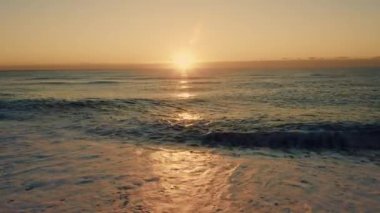 Okyanus dalgaları gün batımında kuma düşer. 