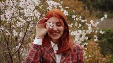 Bahar çiçeği ağacının altında mutlu kızıl saçlı kız. Bahar havası.