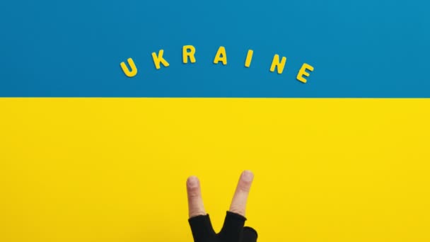 Hand with victory symbol on Ukrainian flag background — Stock Video