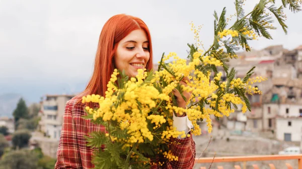 红头发女人手里拿着含羞草花。妇女日 — 图库照片