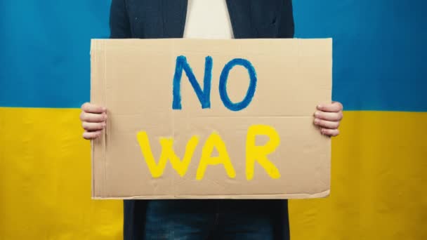 Junge hält in der Hand Karton ohne Kriegstext auf ukrainischem Flaggenhintergrund — Stockvideo