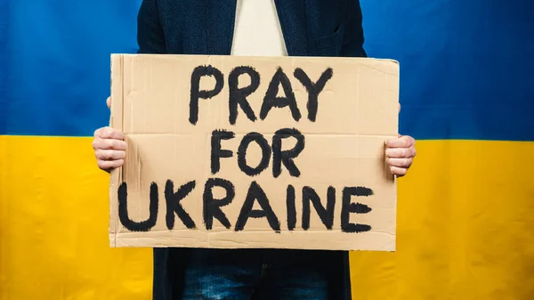 Мальчик держит в руке картон с надписью молиться за Украину — стоковое фото